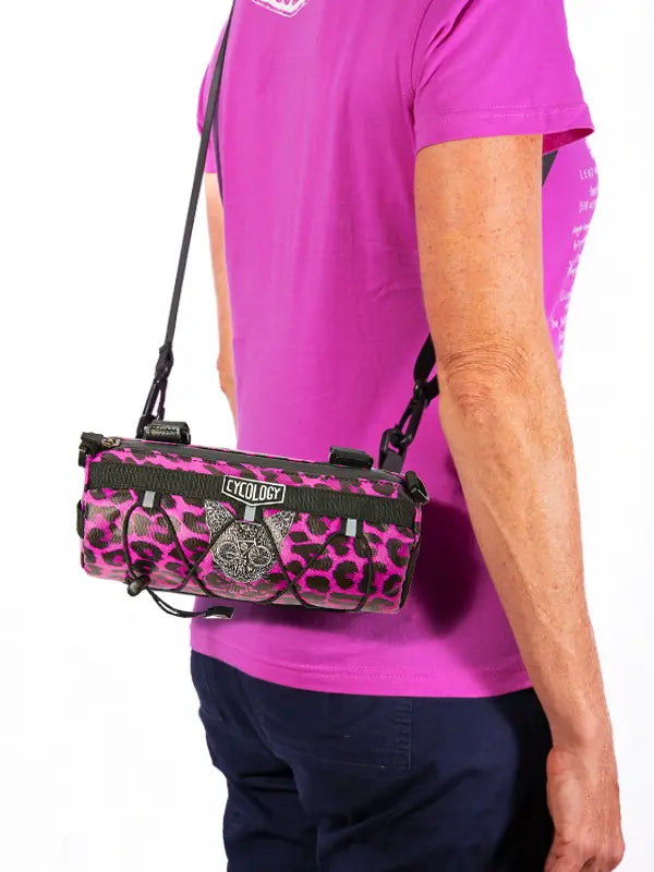 Person wearing a pink and black leopard print bike bag with 'Cyclology' branding.